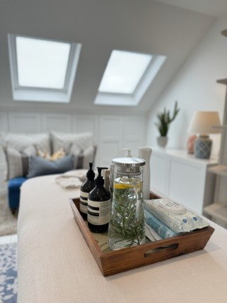 A different view of a tray on a massage table with a water pitcher with herbs.  In the background, windows with bright daylight flooding through.